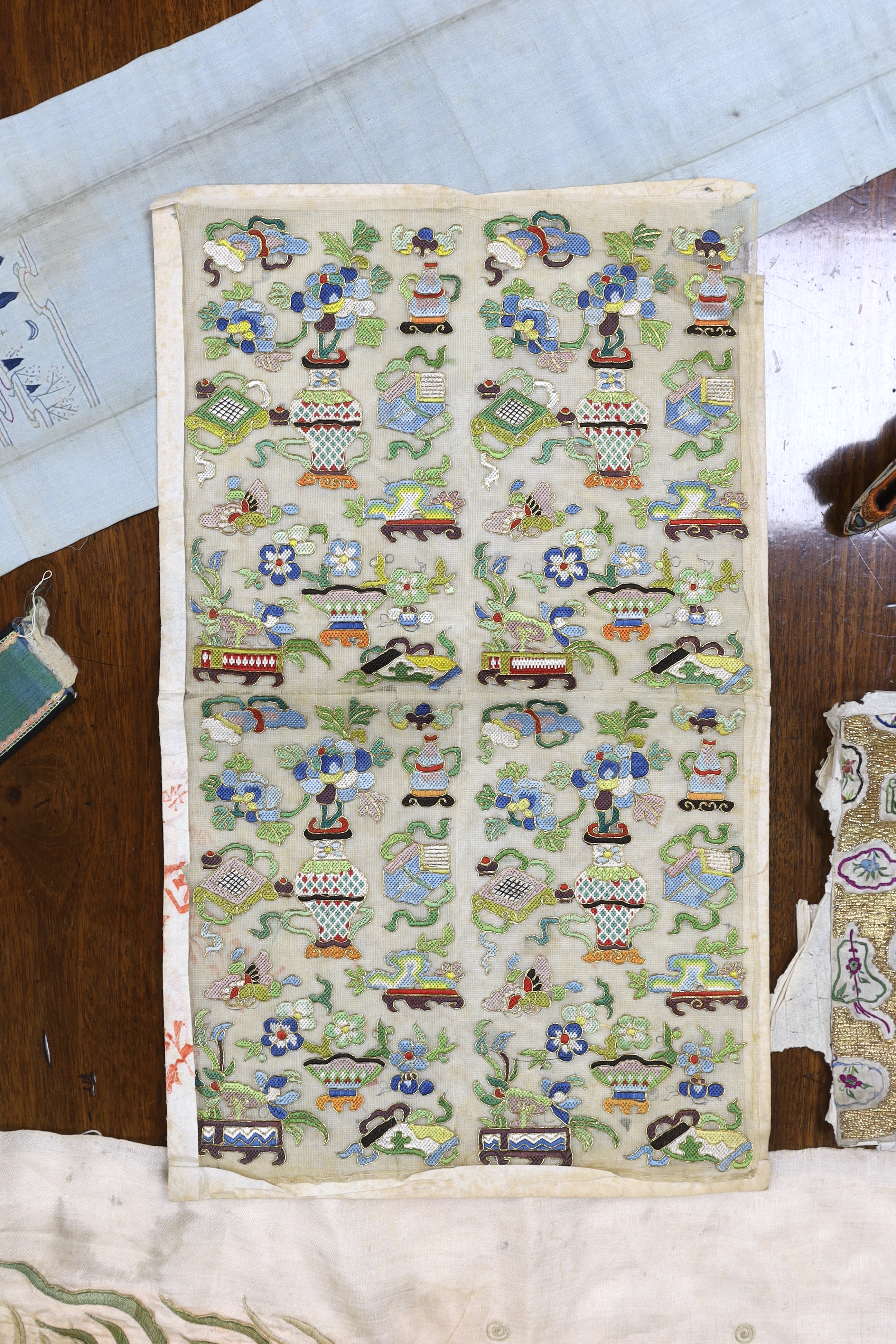 A collection of Chinese embroideries, to include a pair of tasselled embroidered panels to a wedding skirt, two pairs of Chinese children's shoes, a pair of embroidered sleeve bands, a panel of gauze of polychrome silk a